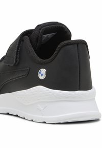 Baskets synthétiques noires avec un col rembourré, une sangle Velcro et une semelle intermédiaire blanche comportant des accents texturés et un détail de logo.