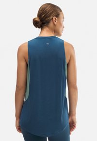 Top sin mangas azul con un dobladillo redondeado, que presenta paneles laterales verdes y un pequeño logo en la parte posterior del cuello. Tela suave y ligera.