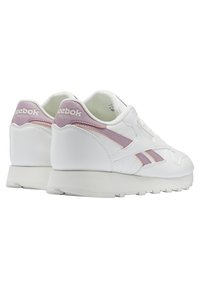 Paire de baskets blanches veganes Reebok avec des accents violet clair, coutures apparentes et semelle texturée, vues de dos et de côté.