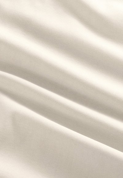 Gładka, kremowobiała tkanina z delikatnymi fałdami i subtelną plecioną fakturą, równomiernie oświetlona, aby podkreślić jej miękkość i układ materiału.
