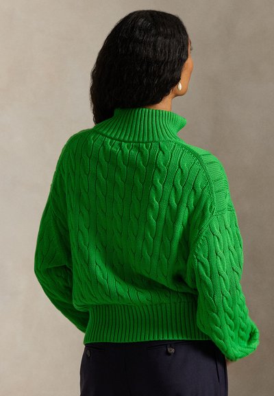 Πράσινο πλεκτό πουλόβερ με υφή από σχέδιο καλωδίου, ψηλό γιακά και ριμπ τελείωμα. Διαθέτει υπερμεγέθη μανίκια και άνετη εφαρμογή.