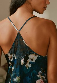 Kvetinový tielko v tmavozelenej farbe s čipkovaným chrbtom, nastaviteľnými ramienkami a hladkou textúrou látky s farebnými kvetinovými vzormi.