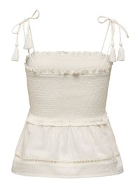 Haut sans manches de couleur crème avec corsage smocké, bords volantés, bretelles nouées avec pompons et partie inférieure évasée et texturée.