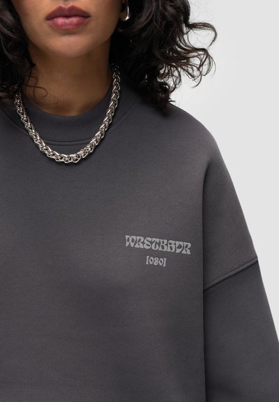 Sweat-shirt gris anthracite en mélange de coton, avec un col rond côtelé et un logo imprimé en gris clair contrastant sur la poitrine.