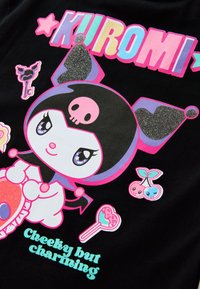 Postać Kuromi z błyszczącym czarnym kapeluszem błazna, różowym symbolem czaszki, otoczona kolorowymi kluczami, wiśniami, lizakiem oraz napisem "Złośliwa, ale urocza."