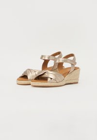 Metallic gold wedge sandals with a knotted strap design, featuring two ankle straps and a woven jute sole for added texture.