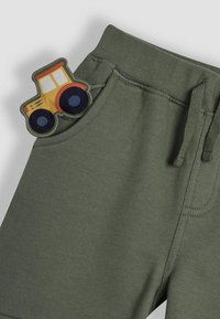 Groene sweatpants van zacht materiaal, met een tractorpatch in geel, rood en blauw op de linkerpocket. Elastische tailleband en trekkoord.