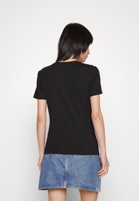 Camiseta de algodón negra con mangas cortas y cuello redondo, combinada con una falda de mezclilla que cuenta con dos bolsillos traseros y un diseño acampanado.