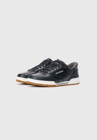 Pair of black Skechers leather sneakers with white midsoles and gum rubber outsoles, displayed on a plain light gray background.