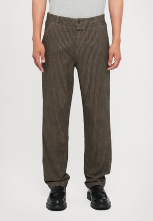 Brown vertical striped pants with a relaxed fit, made of textured fabric. Features a button closure and front pockets. Worn with black shoes.