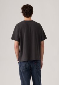 Camiseta de algodón gris con un corte relajado y mangas cortas, con un cuello redondo y sin patrones ni gráficos visibles.