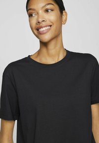 Mustla puuvillane t-särk ümmarguse kaelaaugu ja lühikeste varrukatega. Pehme tekstuur ja mugav lõige, millel on õmblusdetailid ääres.