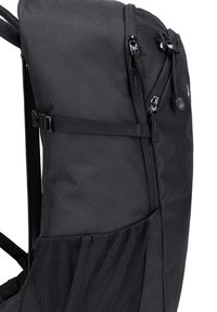 Zwarte rugzak met een zachte stoffen buitenkant, voorzien van een zijvak van gaas, verstelbare schouderbanden, dubbele ritsen en een stevige riem aan de voorkant.