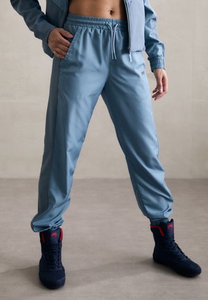 Light blue athletic pants with an elastic waistband and drawstring, featuring side pockets and a smooth, lightweight texture.