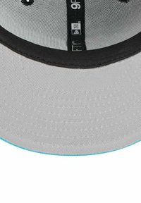 Graue Mütze mit schwarzer Krempe, mit strukturiertem Innenraum und einem türkisfarbenen Akzent entlang der Kante. Das Etikett lautet "9Fifty".