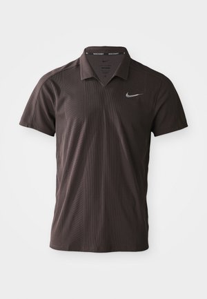 Polo shirt marron foncé en tissu texturé, avec un col à trois boutons et le logo Swoosh de Nike sur la poitrine gauche.