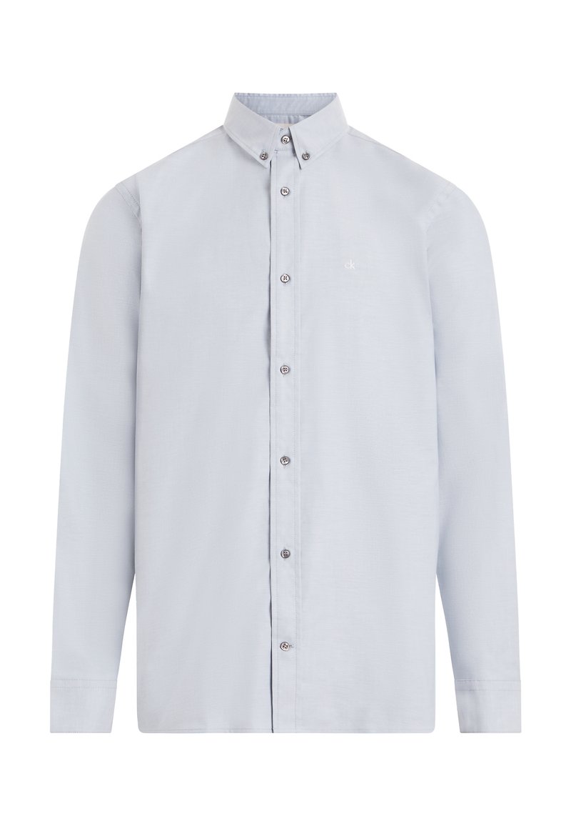 Camisa azul claro de manga larga, fabricada en una tela suave. Presenta un cuello alto, mangas largas y un sutil logo en el lado izquierdo del pecho. Botones plateados.