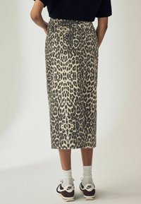 Jeansrock in Leopardenmuster mit hohem Bund, zwei Gesäßtaschen, kombiniert mit schwarz-weißen Sneakers und weißen Knöchelsocken.