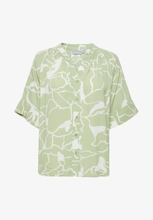 Blouse verte à manches courtes avec un motif abstrait blanc, fermeture à boutons sur le devant et coupe décontractée. Fabriquée en tissu léger avec une texture lisse.