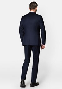 Granatowy garnitur o dopasowanym kroju. Posiada marynarkę na dwa guziki oraz spodnie z gładkim przodem. Gładki materiał, minimalna tekstura i brak widocznych wzorów.