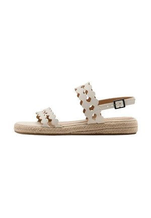 Sandalia plana beige con tiras con bordes ondulados, hebilla en el tobillo y suela de yute trenzado.