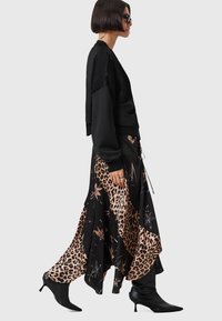 Crna dukserica opuštenog kroja, u kombinaciji s midi suknjom s više uzoraka koja sadrži uzorak leopard printa i cvjetne detalje. Crne štikle s oštrim vrhom.