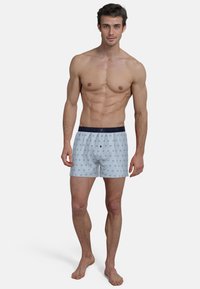 Blue and white striped boxers with a navy elastic waistband, featuring a pattern of small circles and a relaxed fit. Cotton material.