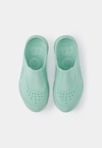 Um par de tamancos de cor verde menta feitos de um material suave e flexível, com buracos de ventilação e uma sola texturizada para aderência.