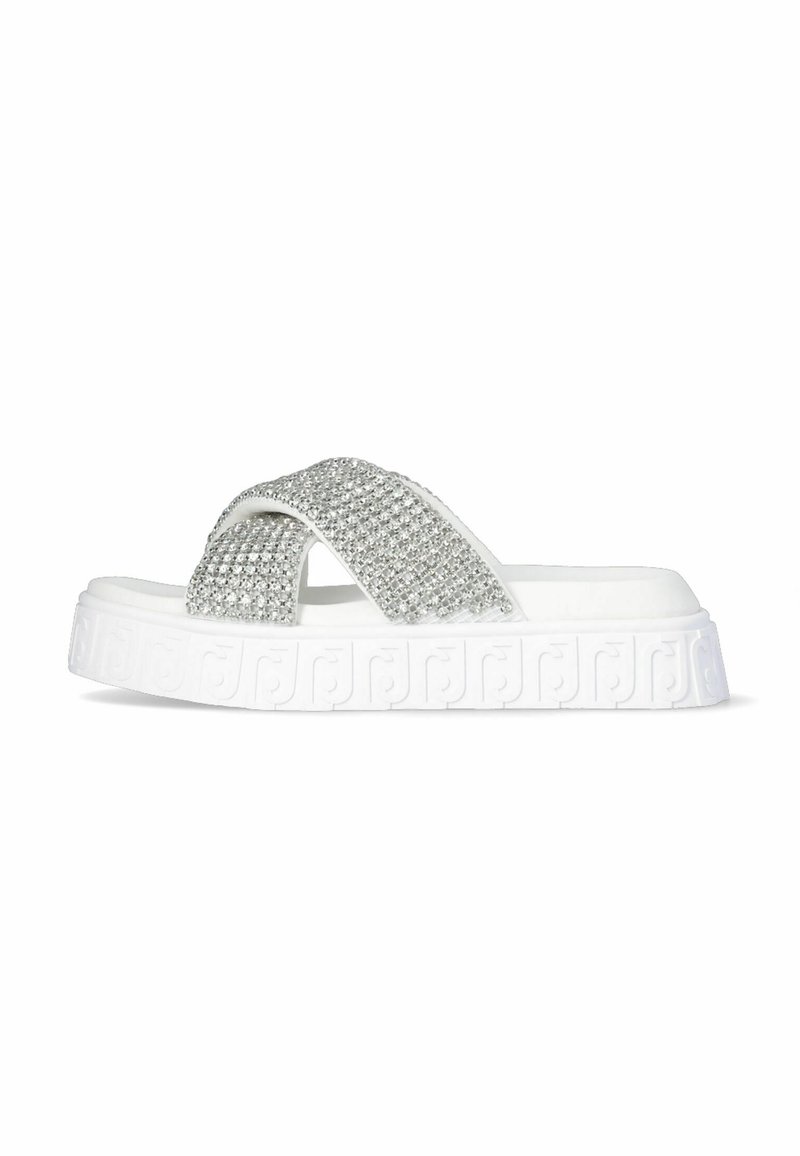 Infradito bianchi con cinghie incrociate ricoperte di strass argento. Suola strutturata con un motivo decorativo a logo. Design piatto.