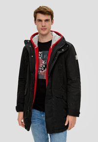 Schwarze, kapuzenjacke mit wasserabweisendem Außenmaterial, rotem und grauem Innenfutter, knöpfen für die Taschen und einem Reißverschluss vorne.