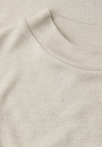 Béžová pletenina s měkkou texturou, hladkým zaobleným výstřihem a jemnými třpytivými vlákny v celém materiálu.