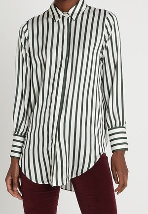 Koszula z długim rękawem w białym kolorze z ciemnozielonymi pionowymi paskami; klasyczny kołnierz, zapinana na guziki z przodu oraz kontrastujące mankiety w paski. Gładka tkanina.