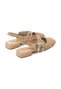 Bottines en suède beige à talon plat et bout pointu, avec des accents de gemmes décoratives sur la bride. Design et texture minimalistes.