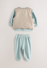 Ensemble pour enfant en deux pièces comprenant un gilet matelassé beige et un sweat-shirt bleu clair avec un pantalon de jogging assorti. Tissu doux, taille élastique.