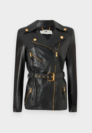 Veste en cuir noir avec taille ceinturée, quincaillerie dorée, design de fermeture éclair asymétrique et quatre poches zippées. Texture lisse.
