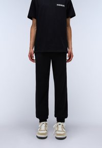 Black cotton T-shirt with short sleeves, paired with black sweatpants. Footwear features beige and white accents and laces.