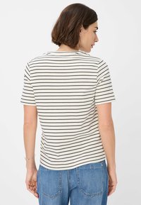 T-shirt a righe con maniche corte, con uno sfondo crema e sottili strisce nere. Materiale morbido e vestibilità rilassata, vista dal retro.