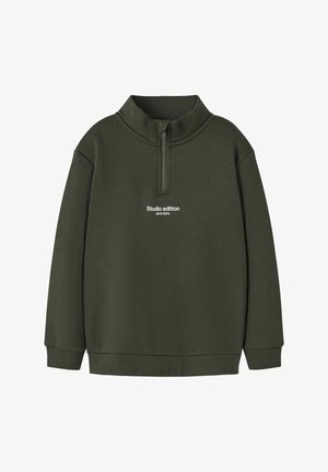 Suéter verde oliva con cuello alto y cremallera, que presenta el texto "Edición de estudio 59°57’03”N" en blanco en el pecho. Material de algodón, ajuste relajado.