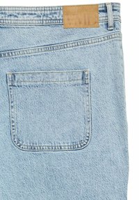 Jeans de mezclilla azul claro con un bolsillo trasero y un parche rectangular de cuero marrón claro con texto en relieve. Tejido de textura fina con un acabado desgastado.