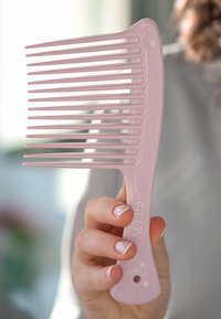 Różowy plastikowy grzebień z długimi, równomiernie rozmieszczonymi zębami i zaokrągloną rączką. Nazwa marki "GLOV" jest nadrukowana na rączce.