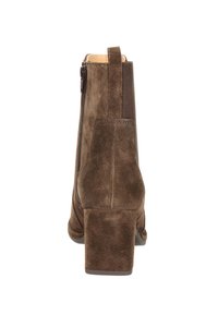 Bottine en cuir suédé marron avec un talon carré, une languette et une fermeture éclair sur le côté, vue de l'arrière sur fond blanc.