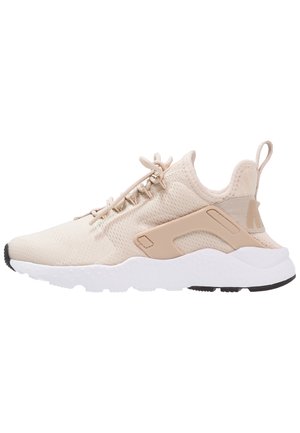 Beżowe buty sportowe z siateczkową cholewką, okrągłym noskiem i amortyzacją w śródstopiu. Posiadają pętelkę do wsuwania oraz gumową podeszwę dla lepszej przyczepności.