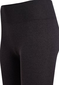 Czarne, prążkowane legginsy z wysokim stanem, wykonane z elastycznego materiału. Tekstura jest gładka, z równomiernym wzorem na całej powierzchni.