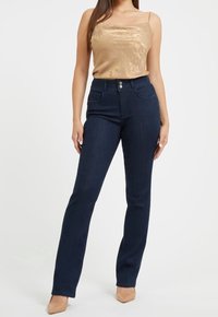 Džínové kalhoty s vysokým pasem, tmavě modré barvy, rovného střihu, vyrobené z denimu. Mají dvě přední kapsy a zapínání na knoflík. Hladká textura.