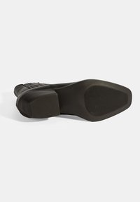 Zwarte schoenzool met een platte vorm, van een gestructureerd rubbermateriaal en een horizontaal geribbeld patroon voor grip. Versterkt hielgedeelte.