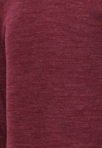 Bordeauxrotes Strickpullovergewebe mit einem strukturierten, melierten Muster, das ein sanftes, warmes Aussehen hat. Keine sichtbaren Beschläge oder Akzente.