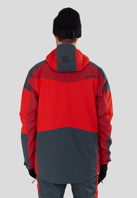 Röd och grå vattenavvisande jacka med huva, med färgblockdesign, texturerat tyg och en logotyp på ryggen. Långärmad, midjan är åtdragen.