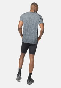 Grijze sport t-shirt met korte mouwen, gecombineerd met zwarte compressie shorts. Inclusief gestructureerde stof en zwarte accenten. Zwarte hardloopschoenen.