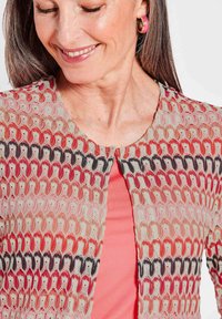 Strickjacke mit einem mehrfarbigen Wellenmuster in Rot, Beige und Schwarz, mit Rundhalsausschnitt und leichter, atmungsaktiver Textur.