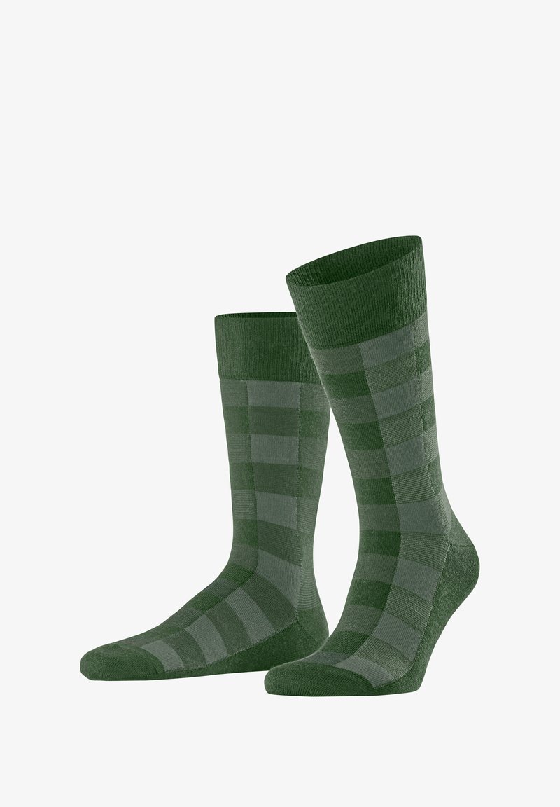 Calzini verdi con un motivo a scacchi che alterna tonalità di verde scuro e chiaro. Cavigliere alte a coste e una texture morbida.
